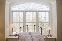A bed positioned in front of a window offers a layout solution in a bedroom with numerous doors.