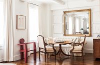 An oversized, rectangular mirror is flanked by artwork in the dining area of designer Mariette Himes Gomez’s home.