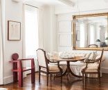 An oversized, rectangular mirror is flanked by artwork in the dining area of designer Mariette Himes Gomez’s home.
