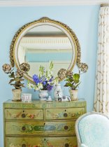 Designer Bunny Williams topped a chest in the bedroom with a large, round, antique mirror.