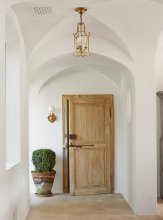 The couple planted boxwoods and other trees and shrubs both outside and inside the home so that “you feel like the lines blur between inside and out, ” says Steve. The small sconce beside the door is antique.