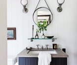 The small round mirror and vintage sconces add vintage charm to the guest bathroom of designer Thom Filicia’s lake house.